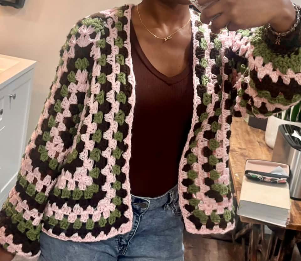 The finished cardigan, worn, in pink, sage and chocolate granny squares
